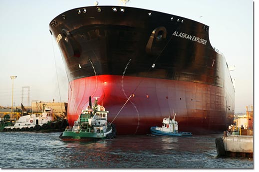 Tugs guide the Alaskan Explorer out of the graving dock as the ship's hull touches the water for the first time.
