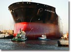 Tugs guide the Alaskan Explorer out of the graving dock as the ship's hull touches the water for the first time.