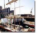 A crane places one of two drive shafts for the ship's&nbsp;twin-screw, diesel-electric propulsion plant. Environmental safety and redundancy will be implemented by segregating the propulsion systems in separate engine rooms, with four engines driving two propellers and twin rudders.