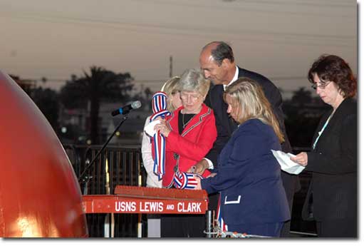 Jane Lewis Sale Henley (in red), the fourth great grandniece of Meriwether Lewis, and Lisa Clark (in blue), the fourth great granddaughter of William Clark, prepare to christen the USNS Lewis and Clark. They are being assisted by Richard Vortmann, president of General Dynamics NASSCO, and their Matrons of Honor, Jody Travers Clark Small (in black) and Ann Meriwether Henley Yauger (in white).
