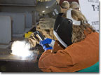 Mrs. Peggy Harris, wife of NASSCO President Fred Harris, welds her initials into the keel of T-AKE 10 on March 17, 2009.