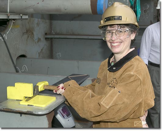 Mrs. Debbie Hamilton drives the first wedge at the T-AKE 4 keel-laying ceremony.