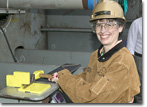 Mrs. Debbie Hamilton drives the first wedge at the T-AKE 4 keel-laying ceremony.