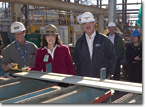 Mrs. Catherine Cunningham observes the measurement of the first steel component cut for T-AKE 6.