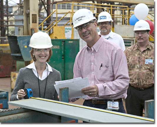 Ms. Robin Wawryznski confirms the measurement of the first steel cut with NASSCO's Manager of Steel Gene Martinelli.