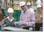 Ms. Robin Wawryznski confirms the measurement of the first steel cut with NASSCO's Manager of Steel Gene Martinelli.