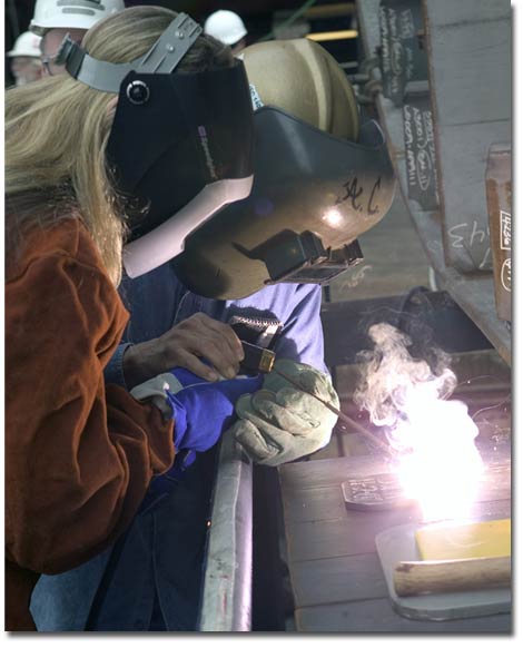 The Navy's Program Manager for Auxiliary Ships, Ms. Bilyana Anderson, welds on the keel of T-AKE 7.