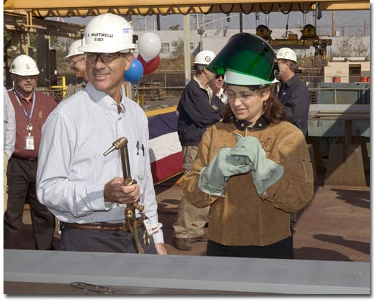 Mrs. Nitananda Crowe prepares to use a cutting torch on the first steel part for T-AKE 8.