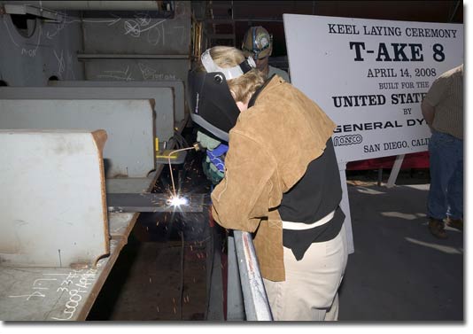 Mrs. Hannah Goddard, wife of PEO Ships RADM Chuck Goddard, welds her initials into the keel of T-AKE 8 on April 14, 2008.
